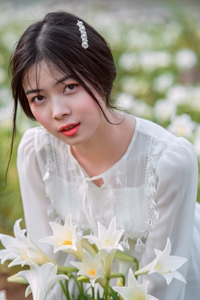 蹲在百合花花海中的白裙美女图片